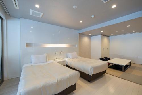a hotel room with two beds and a desk at Namari Onsen Kokoro No Toki Jusangatsu in Hanamaki