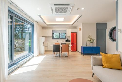 Una sala de estar con un sofá y una mesa y una cocina. en Jeju Aewol Sugar Pension, en Jeju