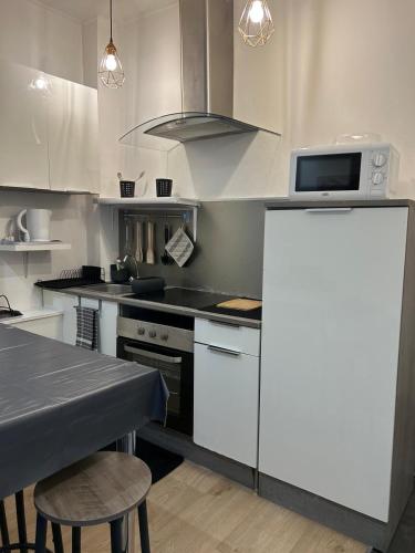 une cuisine avec des appareils blancs et une table avec des chaises dans l'établissement Appartement t3 centre ville de Nice, à Nice