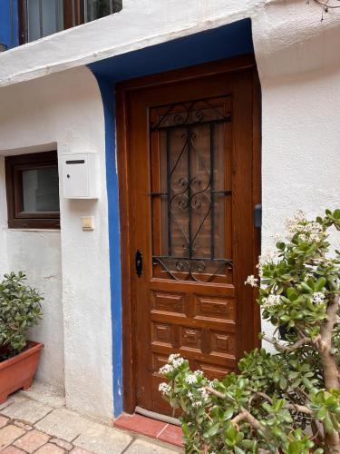 a wooden door on a white building with plants at La Casa Vertical casco histórico de Segorbe in Segorbe