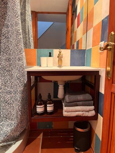 a bathroom with a sink and towels on a shelf at La Casita Vertical casco histórico de Segorbe in Segorbe