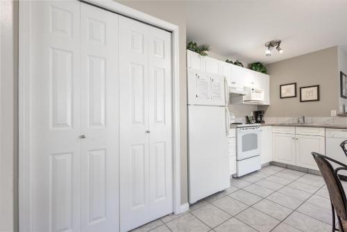 a kitchen with white cabinets and a white refrigerator at Paradise Canyon Golf Resort - Luxury Condo M405 in Lethbridge