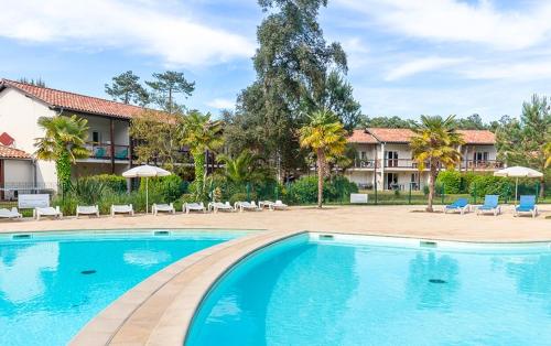 - une piscine avec des chaises et des parasols dans un complexe dans l'établissement Appartement plage, piscine, tennis, nature, à Ondres