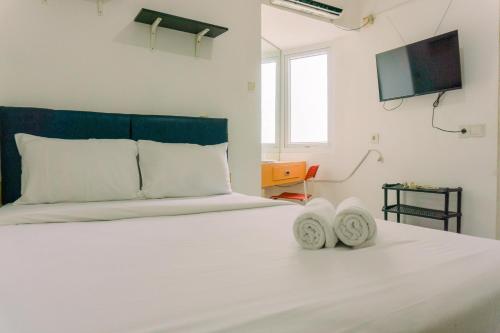 a white bed with two white pillows and a tv at Homey and Tidy Studio Room Aeropolis Apartment By Travelio in Tangerang
