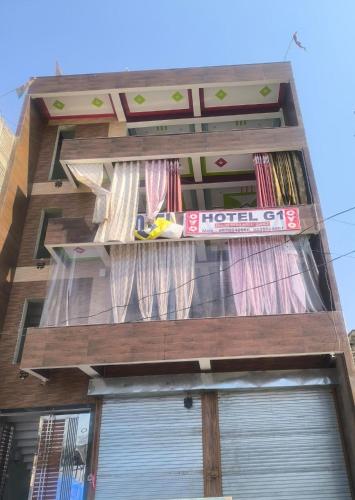 Un edificio alto con una ventana con cortinas. en g one Hotel, en Akbarpur