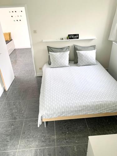 a bedroom with a bed with white sheets and pillows at Flandriens in Bredene