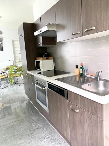 a kitchen with wooden cabinets and a sink and a microwave at Flandriens in Bredene