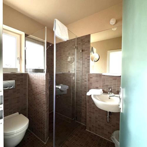 a bathroom with a shower and a sink and a toilet at Hotel Milú in Ludwigsburg