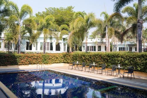 une piscine avec tables, chaises et palmiers dans l'établissement Villa Reina Resort, à Nong Nam Daeng