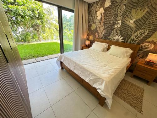 グランベにあるJardin sur la mer de Pointe aux Canonniersのベッドと大きな窓のある寝室