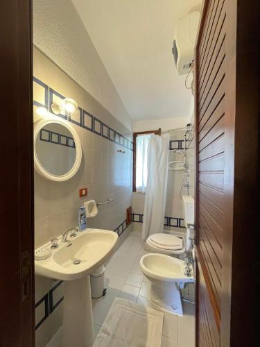 a white bathroom with two sinks and a toilet at Splendida villetta Kal'e Moru in Marongiu