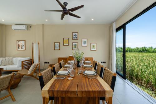 a dining room with a wooden table and a large window at Villa Le Blanc - Tropical Luxury 3BR Villa with Pool & Rooftop Views in Tumbak Bayuh in Tumbak Bayuh