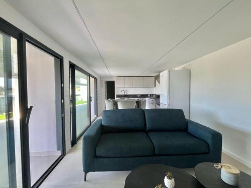 un salon avec un canapé bleu et une cuisine dans l'établissement Appartement à Guidel-Plages, à Guidel