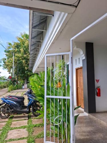 a motorcycle parked next to a house with a gate at Guest House d Valeri in Labuan Bajo