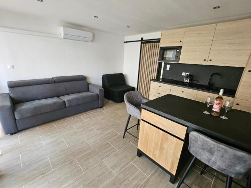 Il dispose d'une cuisine et d'un salon avec un canapé et une table. dans l'établissement Studio chic climatisé avec vue mer et piscine à 100m plage du Môle, au Cap d'Agde