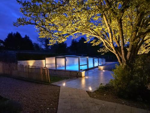 a house with glass walls and a tree at night at Village Collection Le Vauvert in Ormoy-la-Rivière