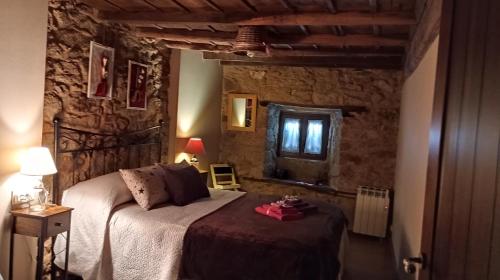 1 dormitorio con 1 cama en una pared de piedra en A Brava, en Sas de Penelas