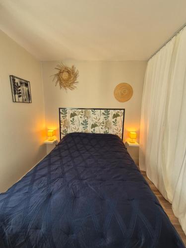 - une chambre avec un lit avec une couette bleue et 2 lampes dans l'établissement L'ancre du Port, à Saint-Quay-Portrieux