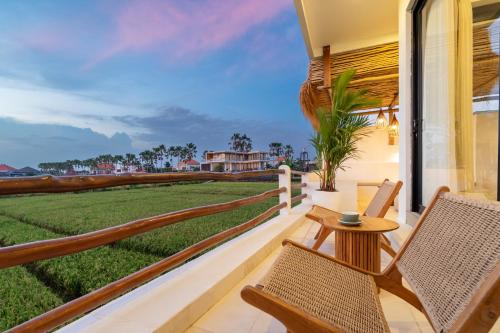 a balcony with chairs and a table and a view of a field at Villa Le Blanc in Tumbak Bayuh