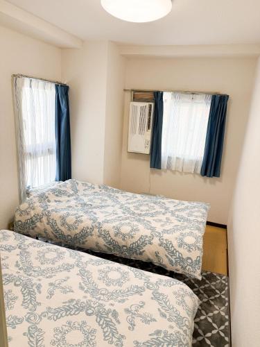 a small bedroom with two beds and two windows at 大曽根駅から徒歩5分人工温泉が24時間楽しめてナゴヤドームまで徒歩で行く事が出来ます in Yadachō