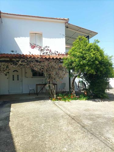 a white house with a tree in front of it at Petrochori Memories Maisonette in Petrochori