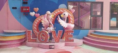 a girl standing in front of a sign that says love at Flamingo Hải Tiến - Căn góc 2 Phòng - View 2 mặt biển in Thanh Hóa