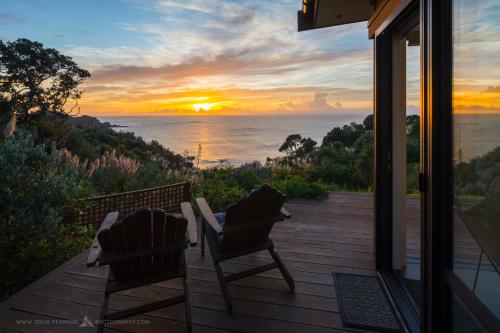 two chairs on a deck with a view of the ocean at Knights in Residence in Tutukaka