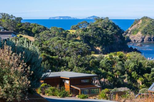 a house on a hill with the ocean in the background at Knights in Residence in Tutukaka