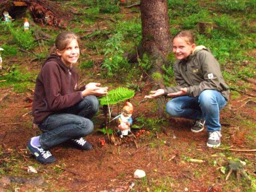 two young girls sitting on the ground next to a plant at Familienbauernhof Christa in Rossleithen