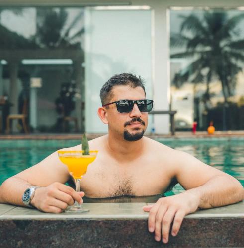a man in a swimming pool holding a drink at River Arc Bolgoda Villa in Panadura