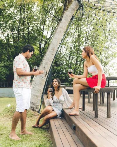 a group of people sitting on a picnic table with wine glasses at River Arc Bolgoda Villa in Panadura