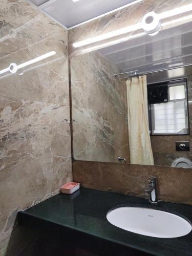 a bathroom with a sink and a mirror at Hotel Shreyas in Pune