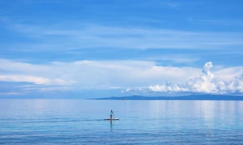 a person on a paddle board in the water at The Lighthouse Resort in Oslob