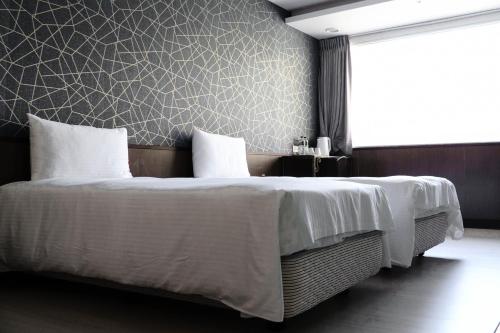 a bedroom with a bed with white sheets and a wall at 星西門行旅 in Taipei