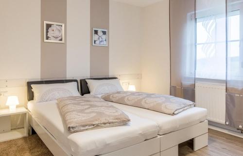 Un dormitorio con una cama con sábanas blancas y una ventana. en Ferienhaus am Rennweg, en Leinach