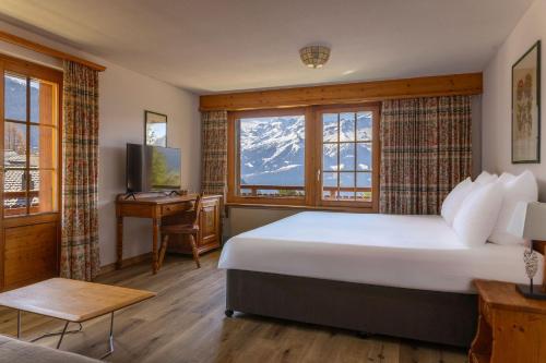 a bedroom with a bed and a desk and a window at Hotel Montpelier in Verbier