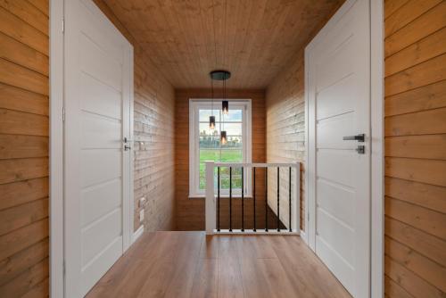 a hallway with white doors and wooden walls at Cozy Sauna House at Sinso Talu in Ülejõe