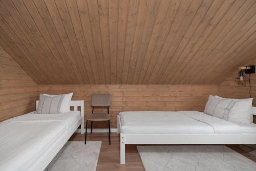 two beds in a room with a wooden ceiling at Cozy Sauna House at Sinso Talu in Ülejõe