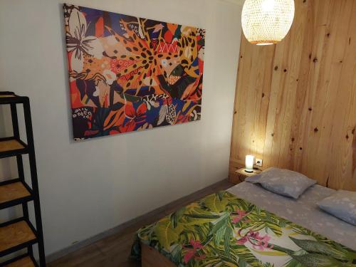 a bedroom with a bed with a painting on the wall at Maisonnette in Le Tampon