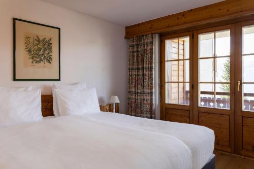 a bedroom with a large white bed and a window at Hotel Montpelier in Verbier
