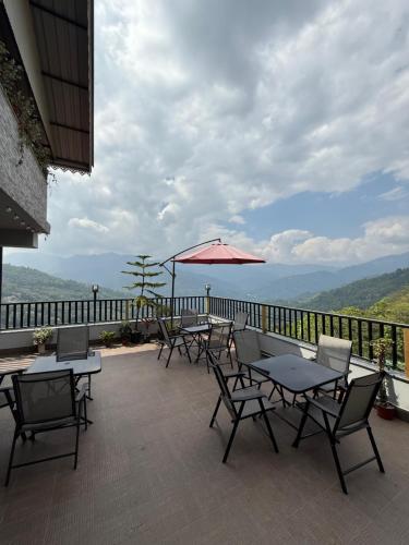 a patio with tables and chairs and an umbrella at Hotel Sky High in Pakyong