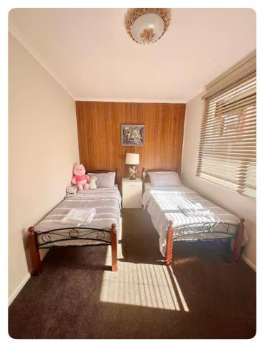 a bedroom with two beds and a pink teddy bear at Jalynn 1 Cottage in Glen Waverley