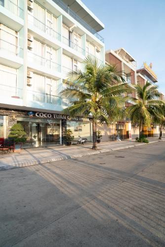 an empty street in front of a building with palm trees at COCO Tuan Chau Hotel in Ha Long