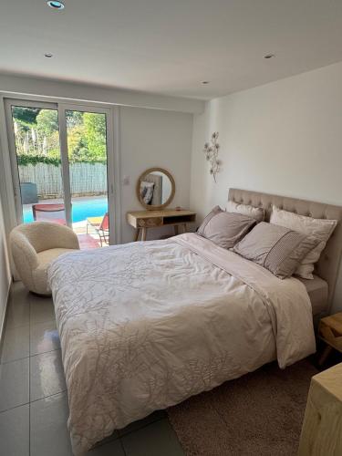 une chambre avec un grand lit et une grande fenêtre dans l'établissement Rez de jardin, piscine privative résidence de standing, à Mandelieu-la-Napoule