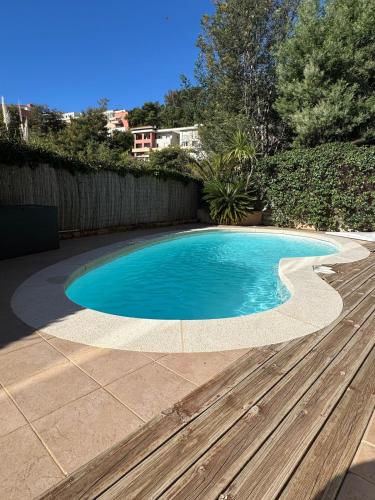 - une piscine dans une cour avec une terrasse en bois dans l'établissement Rez de jardin, piscine privative résidence de standing, à Mandelieu-la-Napoule