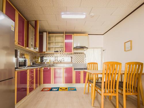a kitchen with wooden chairs and a table and a kitchen with a refrigerator at A spacious and pleasant accommodation for up to 10 people, Haeundae station walking 6 minutes and beach walking 8 minutes in Busan
