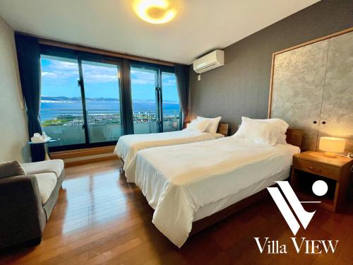 a hotel room with two beds and a large window at 沖縄随一の絶景! 静かなヴィラでゆっくりと最高の旅を! Villa VIEW in Nanjo