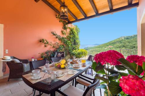 a dining room with a table and some flowers at Villa Adonis by Villa Plus in Agnítsini