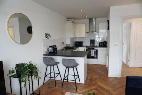 a kitchen with white cabinets and a counter with stools at St Marks Court Apartments in Anlaby
