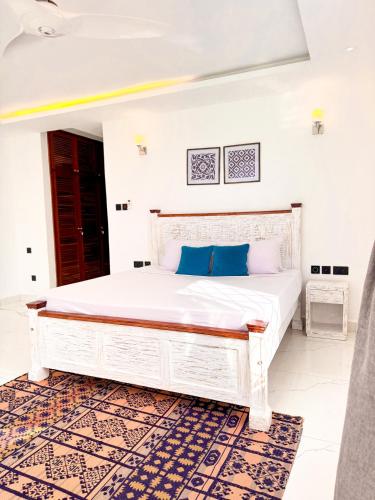 a bedroom with a large white bed with blue pillows at Uttoru Creek Villas-Nyali Mombasa in Mombasa
